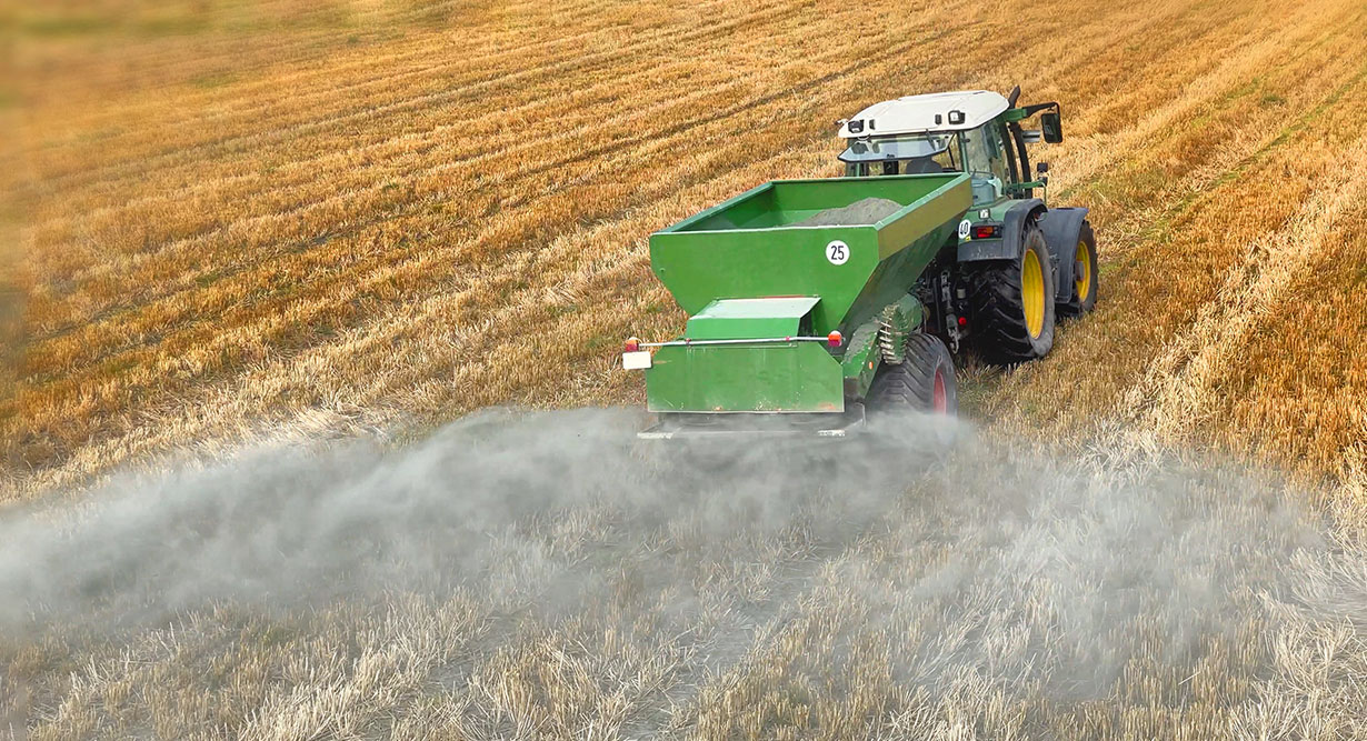 Urgesteinsmehl wird auf einem Feld verteilt 
