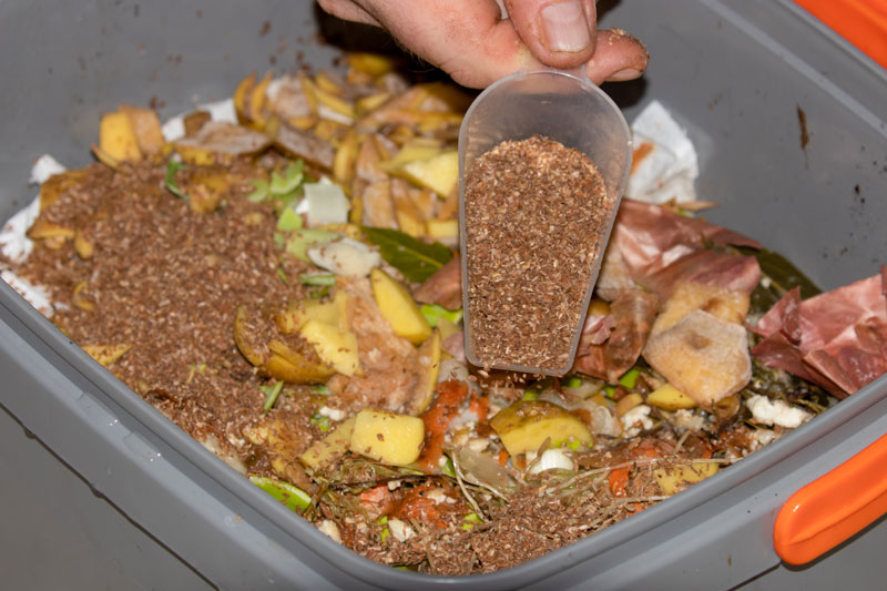Bokashi wird in Komposteimer geschüttet