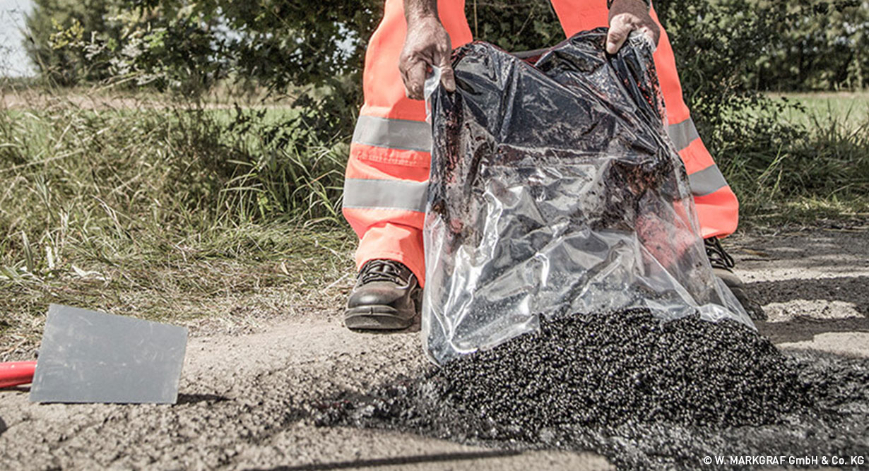Bauarbeiter arbeitet an Asphaltreparatur